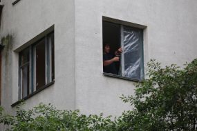 A man covers broken windows with tape after a massive attack in the Solomianskyi district of Kyiv