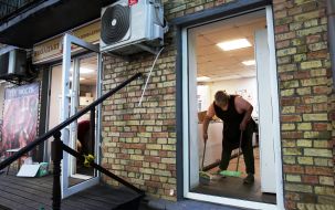 A woman cleans the glass at the door after a massive attack in Kyiv