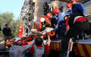 Medics carry a wounded person from the rubble of a house hit by a rocket in the Solomianskyi district of Kyiv