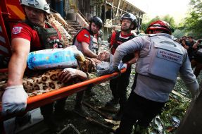 Medics carry a wounded person from the rubble of a house hit by a rocket in the Solomianskyi district of Kyiv