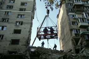 Rescuers work at the site of a direct missile hit on a residential building in the Solomianskyi district of Kyiv