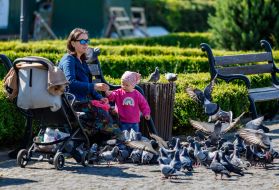 A woman and her daughter feed pigeons
