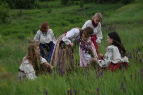 Участницы празднования Ивана Купала собирает букет из полевых цветов