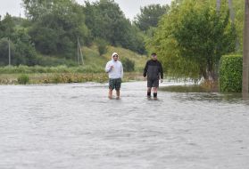 Men walk along a flooded street in the village of Zubra, Lviv region