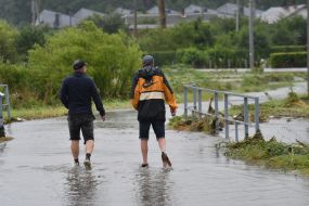 Men walk along a flooded street in the village of Zubra, Lviv region