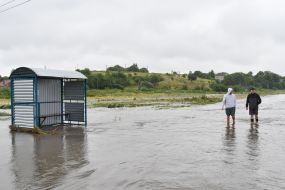 Men walk along a flooded street in the village of Zubra, Lviv region