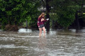 A girl walks along a flooded street in the village of Zubra, Lviv region