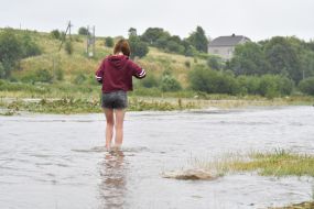A girl walks along a flooded street in the village of Zubra, Lviv region