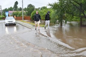 Men walk along a flooded street in the village of Zubra, Lviv region