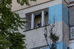 A man cleans glass from a broken window after a drone hit a residential building in Odessa