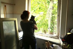 Woman with cat in apartment damaged by shelling