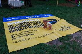 A child stands in the middle of a poster of the Ukrainian eco-movement Let’s do it Ukraine