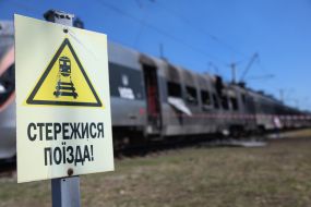A sign reading "Beware of the train" near a severely damaged Intercity+ high-speed train in the high-speed train fleet in Kyiv