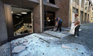 Kyiv residents clean glass near a house after night shelling in Kyiv
