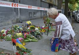 People bring flowers and lamps to the site of Andriy Parubiy's murder in Lviv