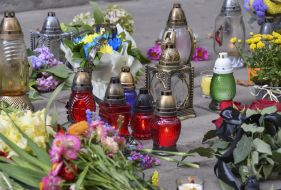 People bring flowers and lamps to the site of Andriy Parubiy's murder in Lviv
