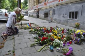 People bring flowers and lamps to the site of Andriy Parubiy's murder in Lviv