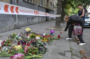 People bring flowers and lamps to the site of Andriy Parubiy's murder in Lviv