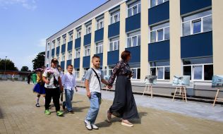 Вчителька веде школярів по шкільному подвір'ю