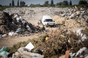 A car with a trailer full of garbage at a natural landfill near Kyiv