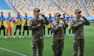 Military personnel perform the Ukrainian anthem before the match