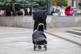 Літній чоловік котить навантажений господарський візок в центрі Києва