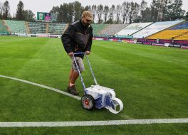 A worker applies markings on a football field.
