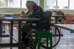 Elderly woman in wheelchair eating lunch in cafeteria