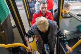 A medic helps a woman get off a bus