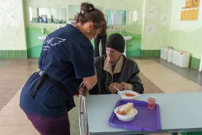Elderly woman in wheelchair eating lunch in cafeteria