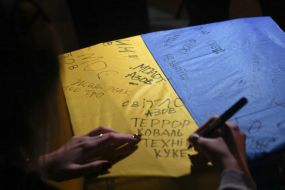 Жінка залишає напис на прапорі України