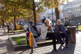 An elderly woman weaves and sells wickerwork on the street in central Kyiv