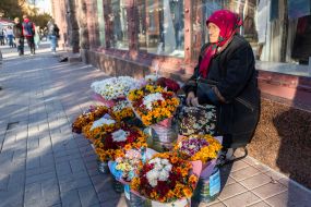 An elderly woman sells bouquets of flowers on the street in the center of Kyiv