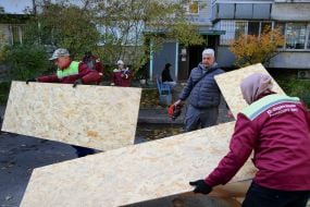 Utility workers prepare plywood to board up windows after a nighttime drone attack in the Desnyanskyi district of Kyiv