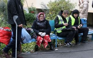 An elderly resident of one of the destroyed apartments sits on a bench with burned hands