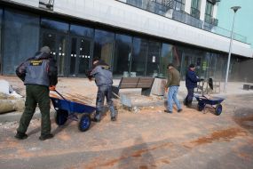 Працівники комунального господарства прибирають уламки та скло біля житлового будинку  після нічної атаки російської федерації  в Подільському районі міста Києва