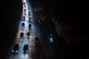 Освещенная автомобильными фарами дорога возле темных жилых домов