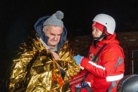 Медики Червоного хреста допомагають чоловіку, який постраждав в наслідок повітряного нальоту дронів, у Харкові