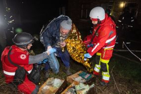 Медики Червоного хреста допомагають чоловіку, який постраждав в наслідок повітряного нальоту дронів, у Харкові