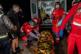 Медики Червоного хреста вантажать у карету швидкої допомоги тіло жінки, яка загинула в наслідок повітряного нальоту російських безпілотників у Харкові