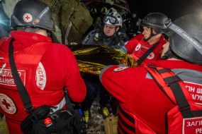 Медики Червоного хреста дістають зі зруйнованого після повітряного нальоту російських безпілотників будинку тіло загиблої жінки  у Харкові