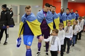 Гравці ФК «Кудрівка» (Кудрівка) виходять на поле, тримаючи за руку хлопчиків у вишиванках