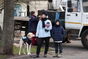 People look at a residential building damaged by shelling