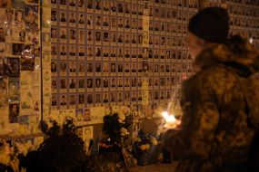 A serviceman holds a candle with the Bethlehem Fire near the Wall of Remembrance on Mykhailivska Square in Kyiv