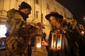 A woman passes the Bethlehem Flame to a soldier on Mikhailivska Square in Kyiv