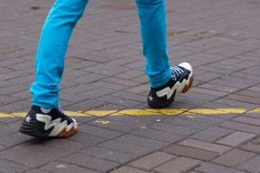 A man in sneakers crosses the yellow line on the sidewalk on a street in Kyiv