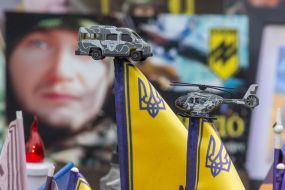 Flags decorated with a toy military vehicle and helicopter in memory of the fallen defenders of Ukraine