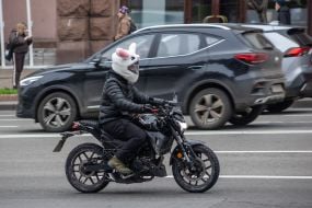 A man wearing a hare helmet rides a motorcycle on a street in Kyiv