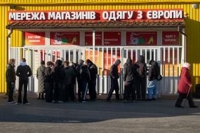 Люди стоять на вулиці біля магазину вживаного одягу в Києві