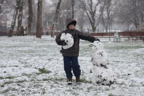 A boy builds a snowman in a park in Kyiv